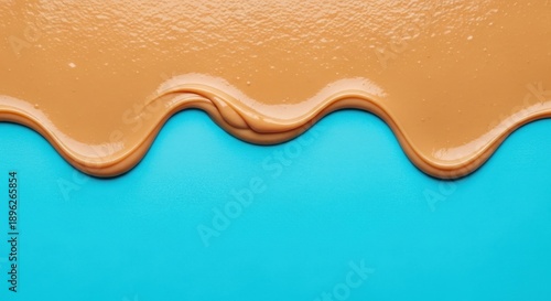 Thick caramel-colored confectionary topping flows across a vibrant cyan surface.
