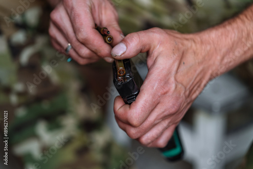 Hands loading ammunition into rifle magazine close up