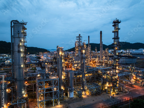 Close up aerial view of distillation towers in oil refinery plant at blue hour for petrochemical engineering industry and chemical manufacturing factory business concept.