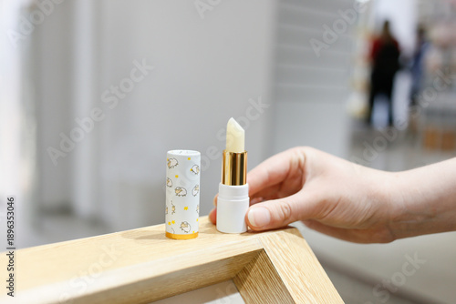 Hand reaching for lipstick on shelf in cosmetics store