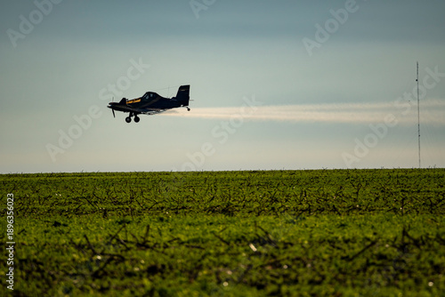 Aerial aircraft spraying agricultural pesticides, fertilizers, and seeds by plane in a soybean plantation on a farm in the Amazon. Concept of agriculture, crop, ecology, environment, airplane.