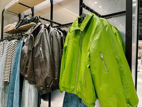 Schilderij op canvas Green and brown women's jackets made of artificial leather on hangers in a cloth