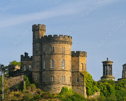 Εκτύπωση καμβά Historic stone tower on Calton Hill in Edinburgh, Scotland, with classical monuments and lush greenery under a clear blue sky
