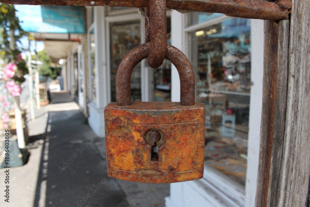 Naklejka premium Rusty Padlock Hanging on Store Closure Sign After Business Hours