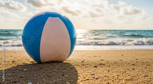 Image of blue and white beach ball on sandy beach, symbolizing summer, vacation, and recreational activity, perfect for travel or holiday concepts