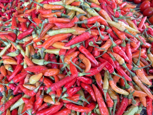 Fototapeta Fresh harvest of spicy red and orange bird's eye chilies at a traditional market
