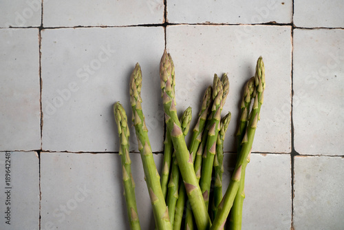 Fresh asparagus spears arranged in a simple composition on a neutral background. Natural food ingredients from top view, ideal for vegetarian, vegan, plant-based and healthy diet concept.