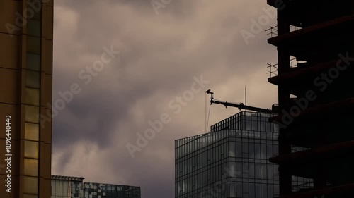 Economic crisis concept. Dark clouds gather around unfinished construction sites and old industrial buildings at sunset. The concept of hard times in the city. Empty place for text.