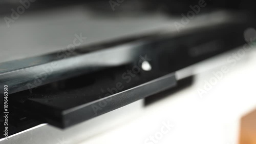 Woman puts a dvd disc into media player.	
