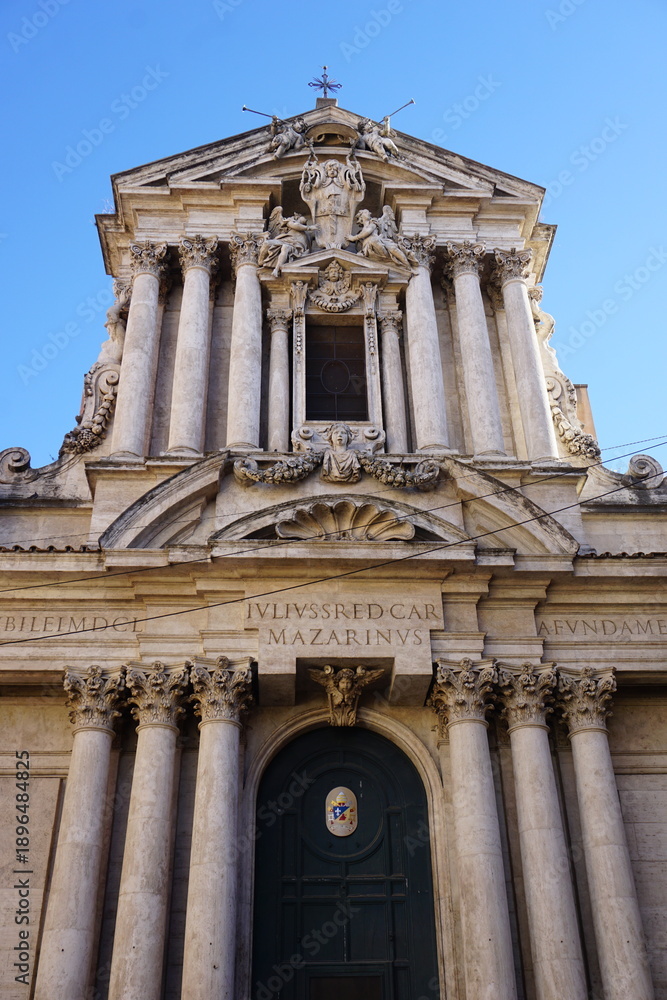 Obraz premium Vertical close up of the front entrance and exterior facade of Santi Vincenzo e Anastasio a Trevi, a historic baroque church near Trevi fountain, Rome, Italy