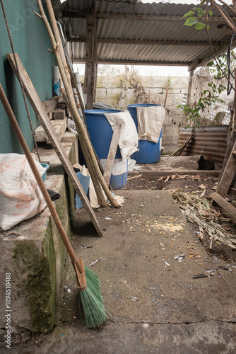 Rural coffee farm workspace with blue fermentation barrels, tools, and drying materials showing the everyday environment of small-scale coffee production.