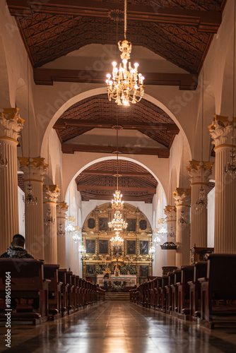 Grand cathedral interior with chandeliers, columns, and altar viewed from the center aisle in San Cristóbal de las Casas, Mexico.