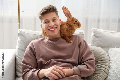 Happy man with cute bunny on sofa at home