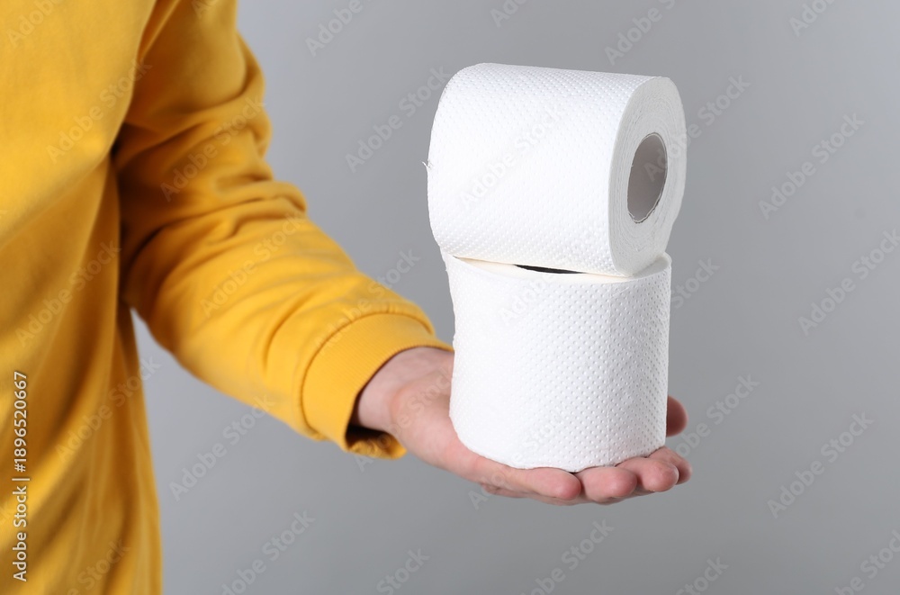 Obraz premium Man with rolls of toilet paper on grey background, closeup