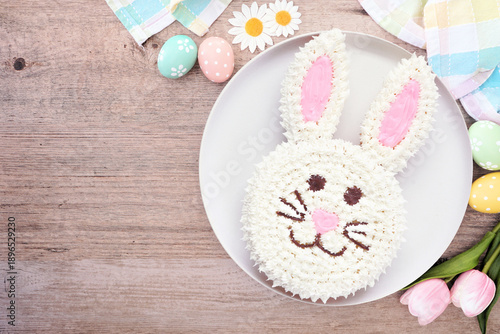 Fun Easter bunny cake. Overhead view table scene over a wood background with copy space.