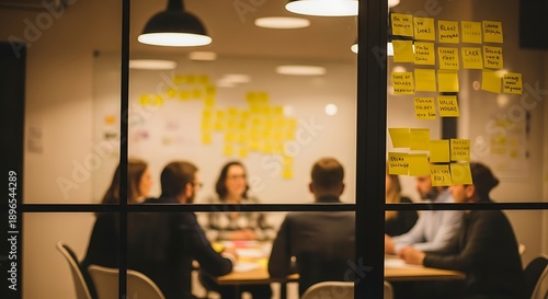 People sitting around a table in a meeting room with sticky notes on a glass wall chairs