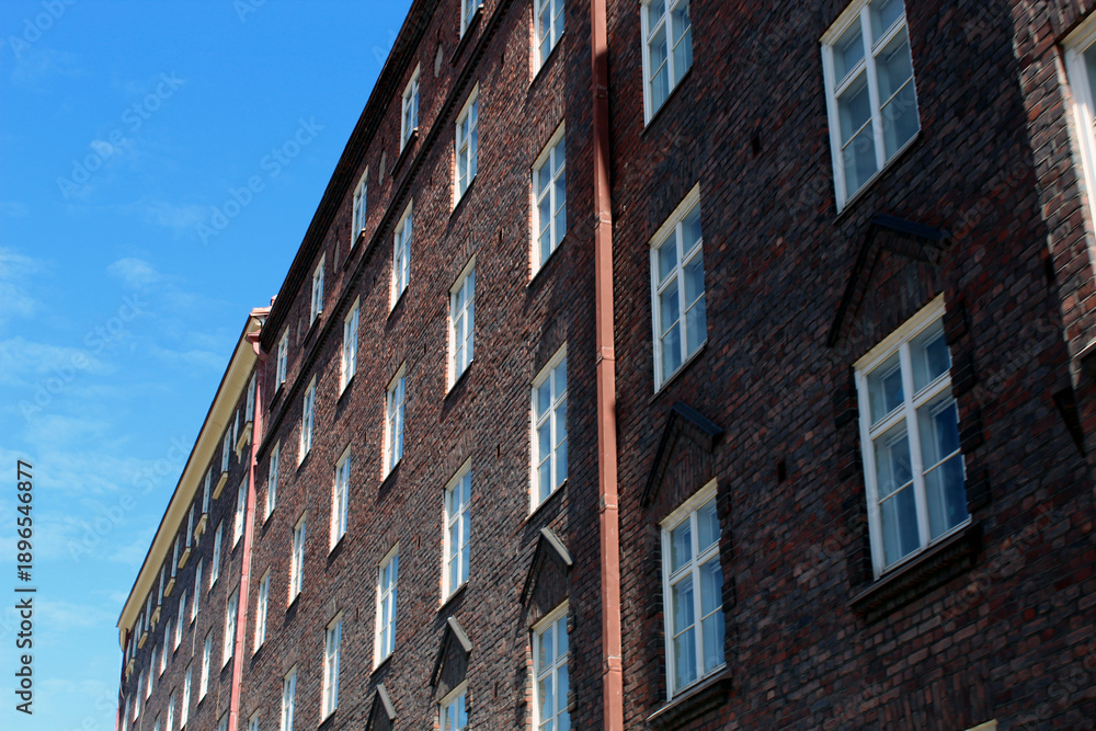 Fototapeta premium Long Brick Apartment Building Facade With Windows And Sky