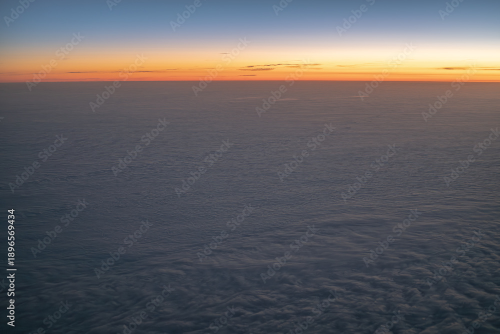 Fototapeta premium Horizon over clouds during sunrise from airplane