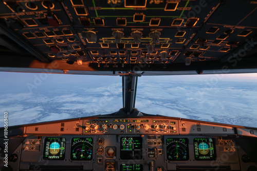 Airplane cockpit flying over norwegian winter landscape at sunrise