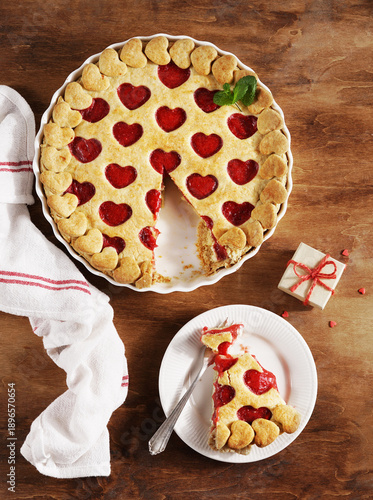 Cooking dish and plate with heart-shaped sweet strawberry pie and cookie hearts for Valentine's day on wooden background