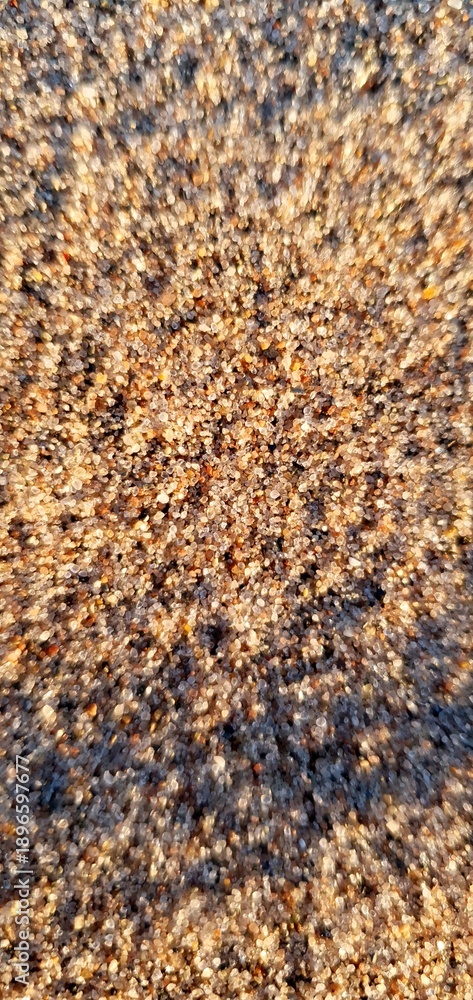 Fototapeta premium Sunlit natural sand texture with warm golden tones and fine sparkling grains. Abstract beach background with soft shadows and detailed surface pattern for design use