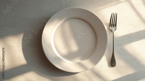 Empty plate and fork on a table with soft natural light casting shadows