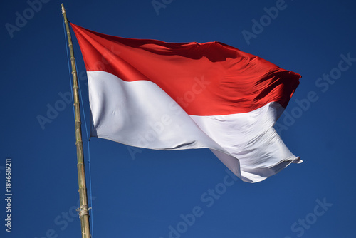 The Indonesian red and white flag against a blue sky
