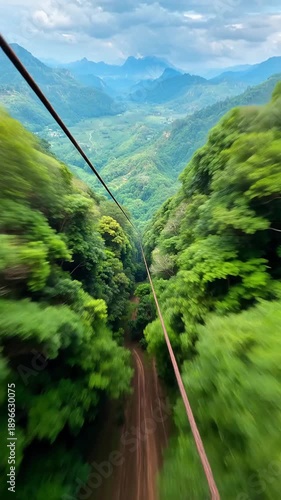 Riding a zipline through a lush green mountain valley with a cloudy sky above