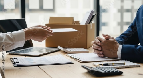 Employee hands over a document to a manager across a desk during a work transition discussion.