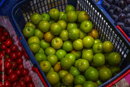 Juicy green apples in a plastic basket at the market. Fresh harvest of organic fruits and vegetables. Top view.