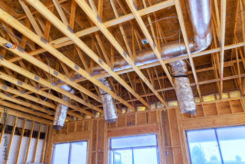 Wooden beams, ducts are inside house under construction, with over celling