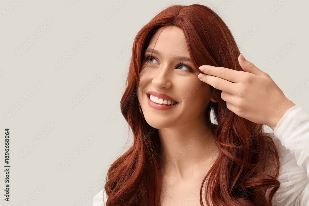 Obraz premium Beautiful young woman in red wig on light background, closeup