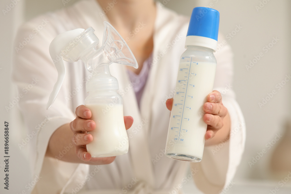 Fototapeta premium Woman with breast pump and bottle of milk in bedroom, closeup