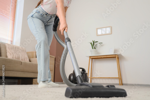Young woman cleaning carpet...