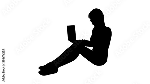 Silhouette of a Woman Sitting on the Floor Using a Laptop
