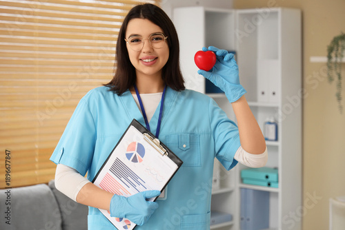 Female doctor with heart and clipboard in office. World Health Day