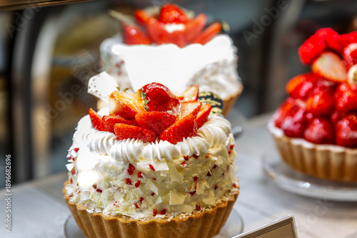 A shortcrust pastry tart with cream and fresh strawberries on display. A delicious, fresh dessert. Close-up.