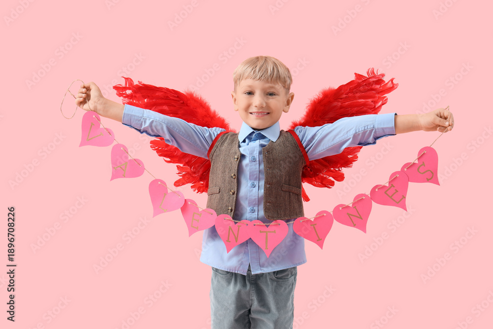 Obraz premium Cute little happy boy in cupid wings with heart-shaped garland on pink background. Valentine's Day celebration
