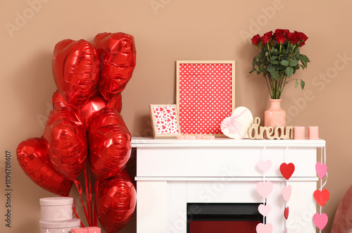 Fireplace with heart-shaped balloons, gifts and roses near beige wall. Valentine's Day celebration