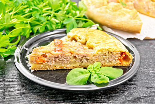 Galette with minced meat and peppers in plate on dark board
