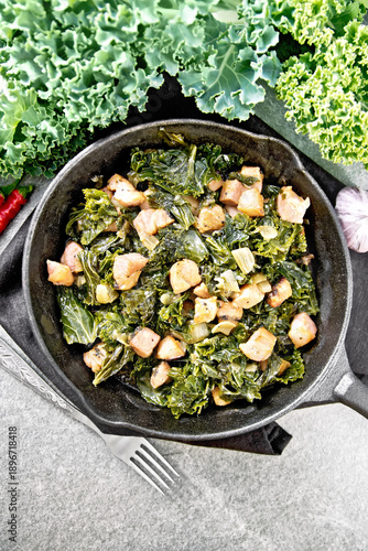 Kale cabbage with bacon in pan on stone table top