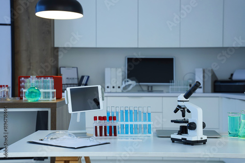 Microscope, test tubes and tablet on table in medical laboratory