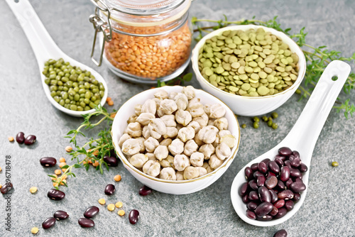 Legumes in bowls and spoons on stone table