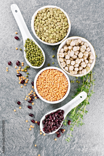 Legumes in bowls and spoons on stone top