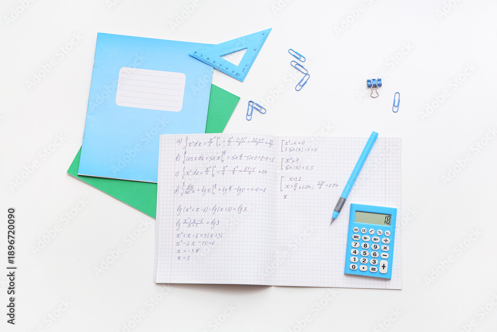 Fototapeta premium Open copybook with math formulas and stationery on light background