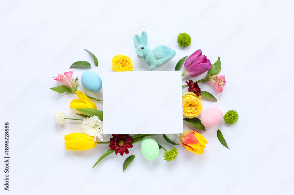 Fototapeta premium Blank card with toy bunny, Easter eggs and flowers on white background