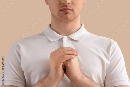 Young man praying on beige ...
