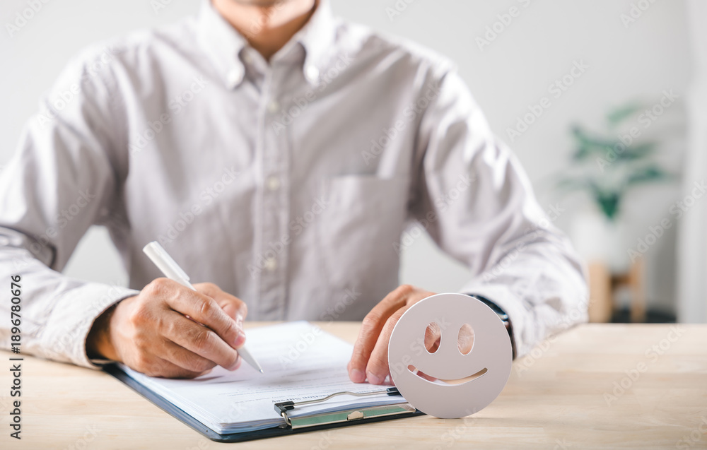 Fototapeta premium Survey form completion by man writing customer feedback for service satisfaction, happy face icon indicating excellent experience review ensures positive business quality check