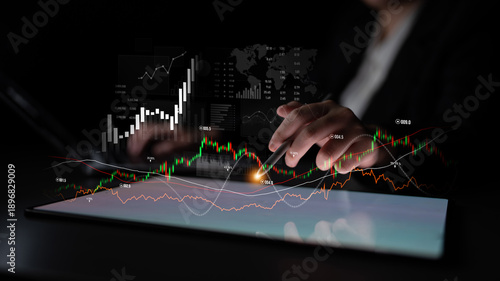 Billede på lærred A business professional reviews financial data on a tablet with stock market graphs and charts, highlighting trends and investment strategies in a modern workspace