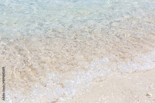 Clear sea water with a sandy bottom and sun glare. Relaxation and tranquility on vacation. Background. Space for text.